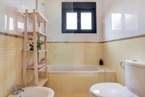 a bathroom with a tub and a toilet and a sink at Villa Norteventura in Majanicho