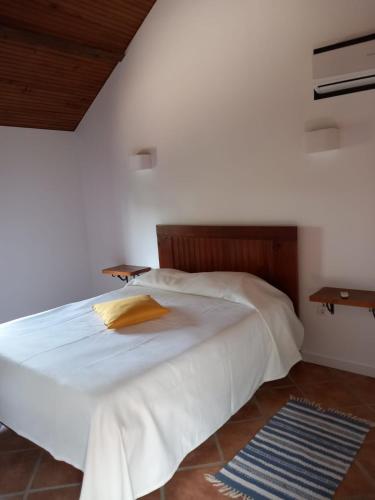 a bedroom with a large white bed with a wooden headboard at Casa de Andrães - Glicíneas in Marco de Canaveses