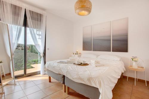 a white bedroom with a large bed with white sheets at Villa Norteventura in Majanicho