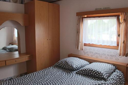a bedroom with two beds and a window and a mirror at Chalet du Lièvre in Hannappes