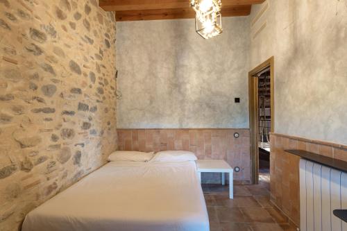 a bed in a room with a stone wall at Masia Can Divi in La Ametlla