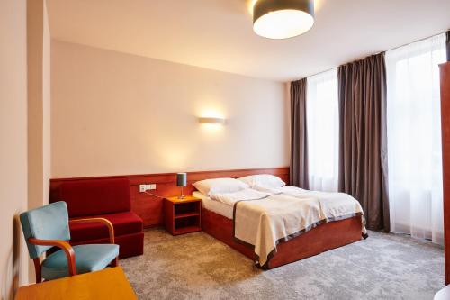 a hotel room with a bed and a chair at Hotel Terasa in Vimperk