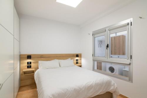 a bedroom with a white bed and a window at S Q Playa de Sardina in Gáldar