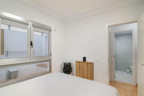 a bedroom with a bed and a window and a bathroom at S Q Playa de Sardina in Gáldar