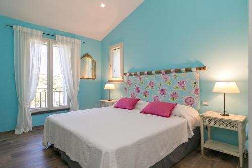 a blue bedroom with a bed with two pink pillows at Casetta Maya in Riparbella
