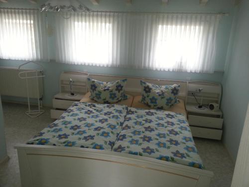 a bedroom with a bed and two windows with curtains at Fewo Singler in Hofstetten