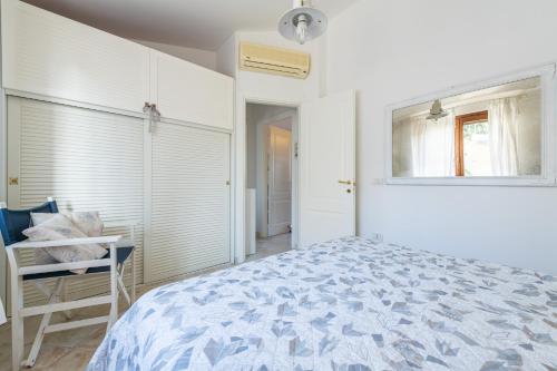 a white bedroom with a bed and a window at Attico il Mandorleto in Villasimius