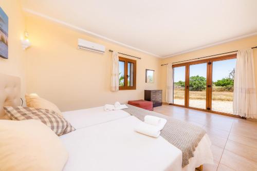 a bedroom with a white bed and a large window at Sa Xorca in Santanyi