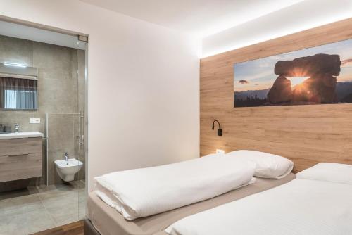 a bedroom with a white bed and a bathroom at Aster Moments Apt Max in San Genesio Atesino