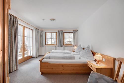 a bedroom with a bed and a table and windows at Petrushof Ferienwohnung Taubensee in Oberwössen
