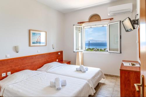 a bedroom with two beds and a window with the ocean at Anemologio 304 Tinos in Agios Ioannis