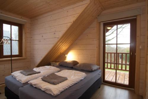 two beds in a room with wooden walls and windows at Houten Villa Dirk in Den Ham