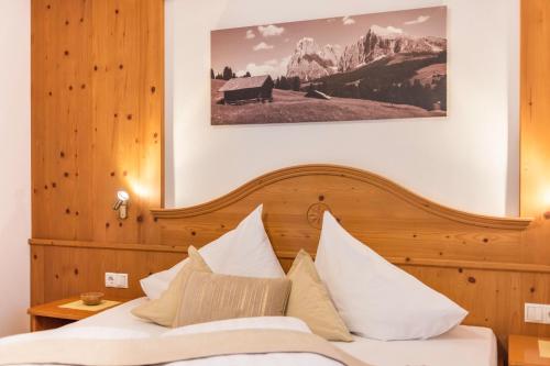 a bedroom with a bed with white pillows at Kristiania Apartement Typ A1 in Siusi