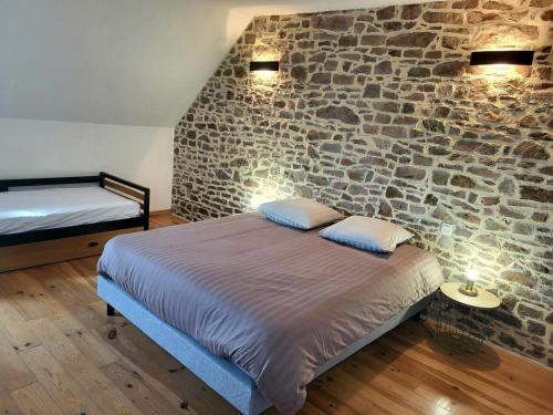 a bedroom with a bed and a stone wall at Petit Loft, Maison Bord De Mer in Pirou
