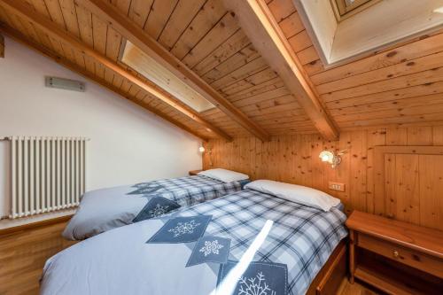 two beds in a small room with wooden ceilings at Ciasa Sommavilla Mansarda in Vigo di Fassa
