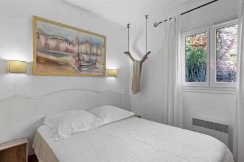 a white bedroom with a bed and a window at Chez Skadi in Roquebrune-sur-Argens