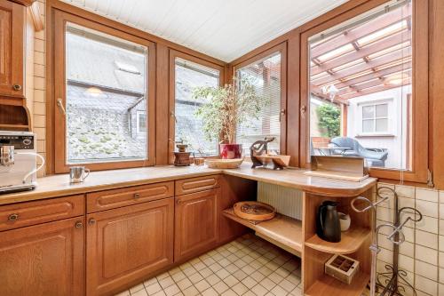 a kitchen with wooden cabinets and windows and a sink at Fewo Moseljuwel mit Sauna und Pool in Traben-Trarbach
