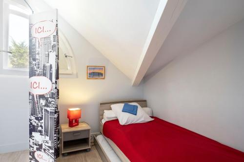 a small bedroom with a red bed and a window at Appartement Le Moulleau in Arcachon