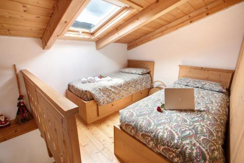 a attic bedroom with two beds and a laptop computer at Taulain Gotrosio in Valdisotto