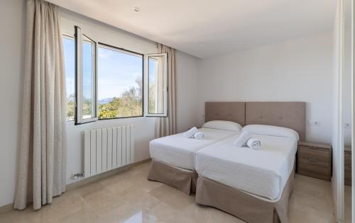 a bedroom with two beds and a large window at Can Luciana in La Aranjasa