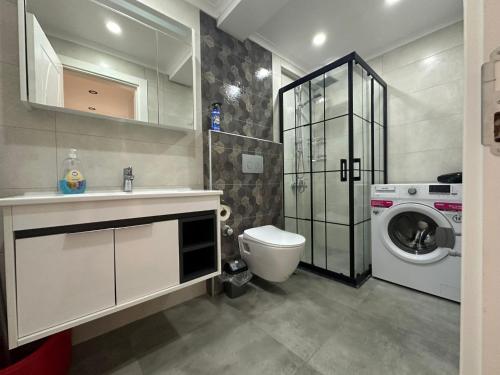 a bathroom with a sink and a washing machine at Alas Garden City Apartment Fethiye in Fethiye