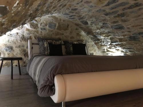 a bed in a room with a stone wall at Cocoon,Vue Montagne,Jacuzzi privé in Mostuéjouls