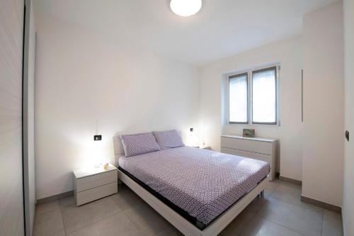 a white bedroom with a bed and a window at Appartamento 6 Il Tornante in Nesso