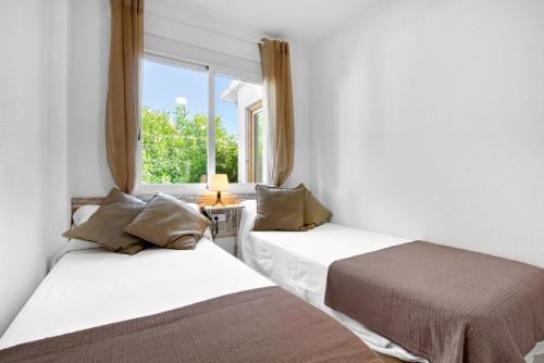 two beds in a room with a window at Ca Blanca Paraíso ll in Denia