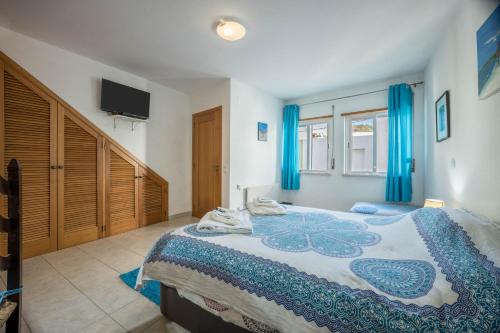 a bedroom with a large bed with blue curtains at Casa Da Paz in Salema