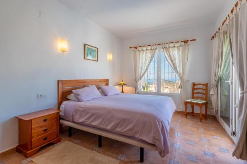 a bedroom with a bed and a chair and a window at Casa Maravilla in Benitachell