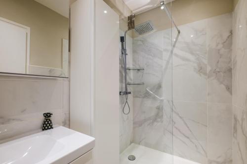 a white bathroom with a shower and a sink at Appartement Sea View in Nice