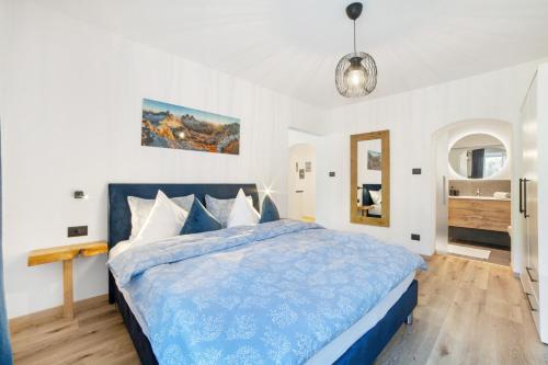 a bedroom with a blue bed and a bathroom at Appartment Riffl Anna in Rifiano