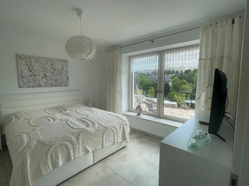 a white bedroom with a bed and a window at Ferienwohnung Sonnenhöhe in Greiz