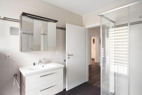 a white bathroom with a sink and a mirror at Gästehaus Lean in Potsdam