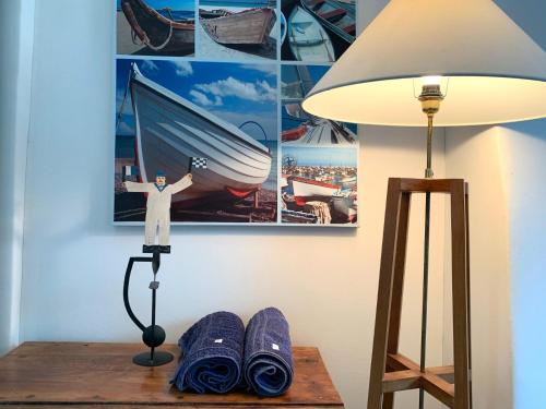 a table with a lamp and a picture of a man on a boat at Villa Kergariou in Clohars-Carnoët