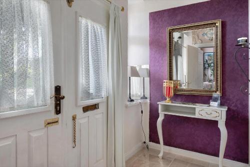 a hallway with a mirror and a door with purple walls at Die Kleine Ferienwohnung in Schneverdingen