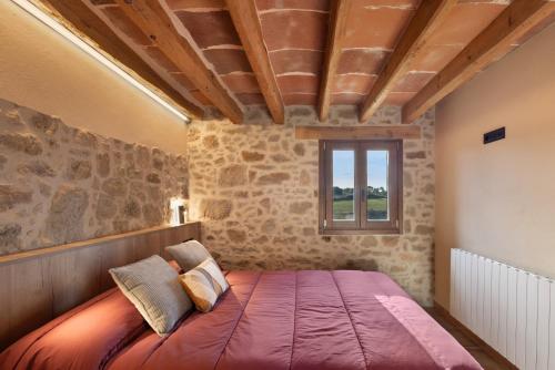 a bedroom with a bed in a room with stone walls at Cal Trumfet in Caserras
