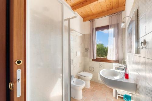 a bathroom with a toilet and a sink and a shower at Villa Is Sorrisi in Gonnesa