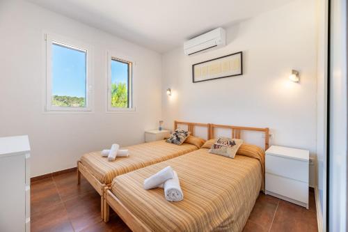 two beds in a room with two windows at Es Camp in Cala Saona