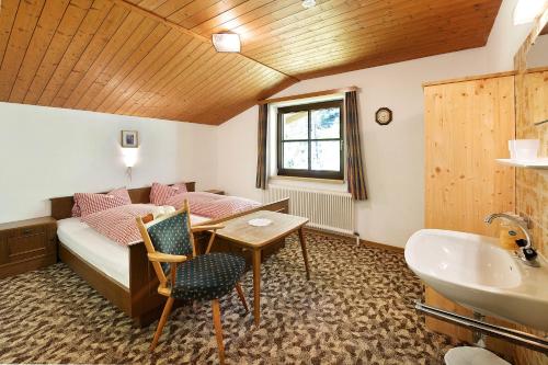 a room with a bed and a desk and a sink at Alpenchalet Lacknerbrunn bis 30 P in Mayrhofen