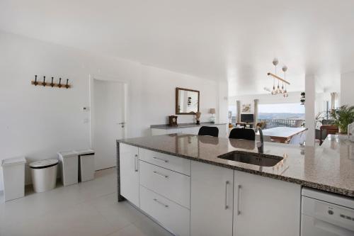 a white kitchen with a sink and a counter at Peace House Lourinhã in Lourinhã