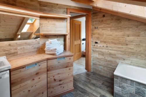 a bathroom with wooden walls and a counter with towels at Ciasa Badia in Pozza di Fassa
