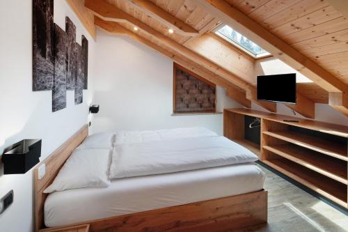 a bedroom with a bed in a room with wooden ceilings at Ciasa Badia in Pozza di Fassa