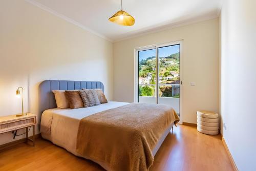 a bedroom with a bed and a large window at Casa Sol in Caniço