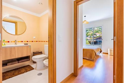 a bathroom with a toilet and a sink and a mirror at Casa Sol in Caniço