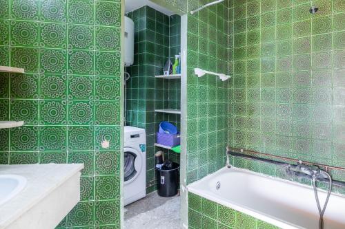 a green tiled bathroom with a tub and a washing machine at Calpe primera linea con piscina in Casas de Torrat