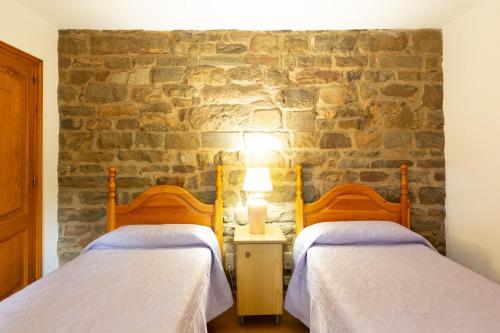 two beds in a room with a stone wall at Ca la Irene I in Begur