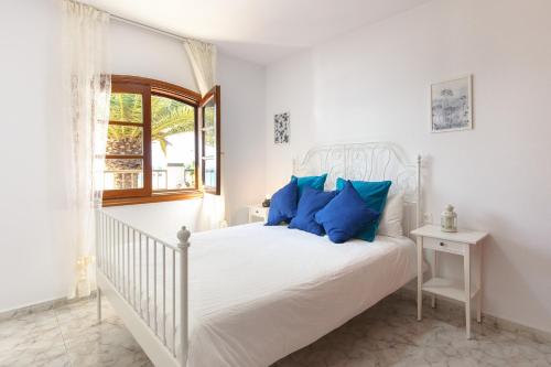 a bedroom with a white bed with blue pillows at Salitre in Playa Honda