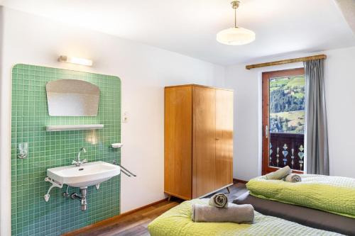 a bathroom with a sink and a green tile wall at A Nett’s Nest - Haus in Hainzenberg