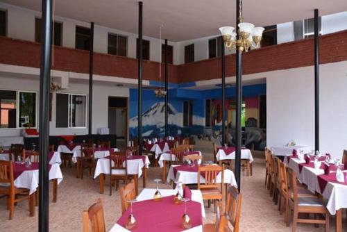 a dining room with tables and chairs with red table cloth at Keys Hotel Mbokomu Branch in Moshi